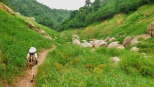 Young woman backpacker walking along the road to the mountain.