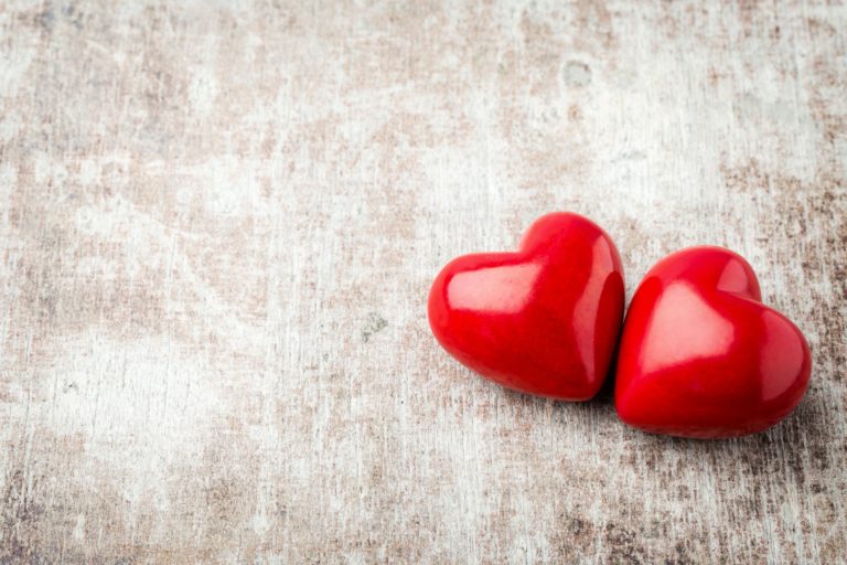 Heart. Red stone hearts on the wood background.